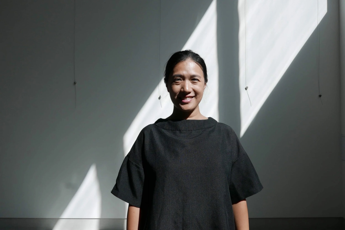Shell Li, AIA, founder of Highly Sensitive Design, standing in a band of sunlight